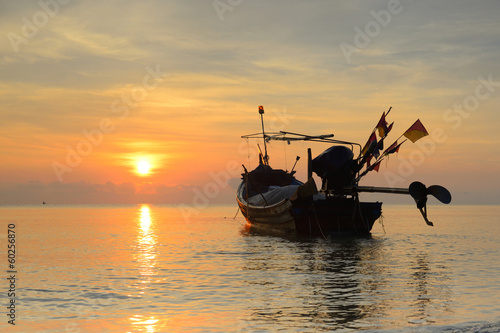 fishing boat with sunrise backdrop.