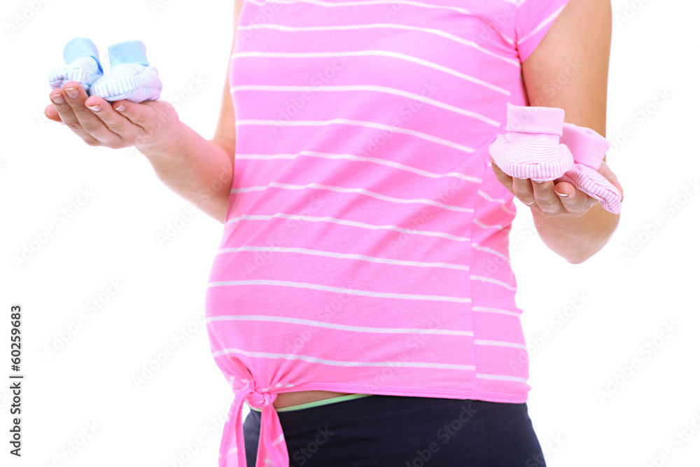 Naklejka premium Pregnant woman holding blue and pink baby shoes isolated