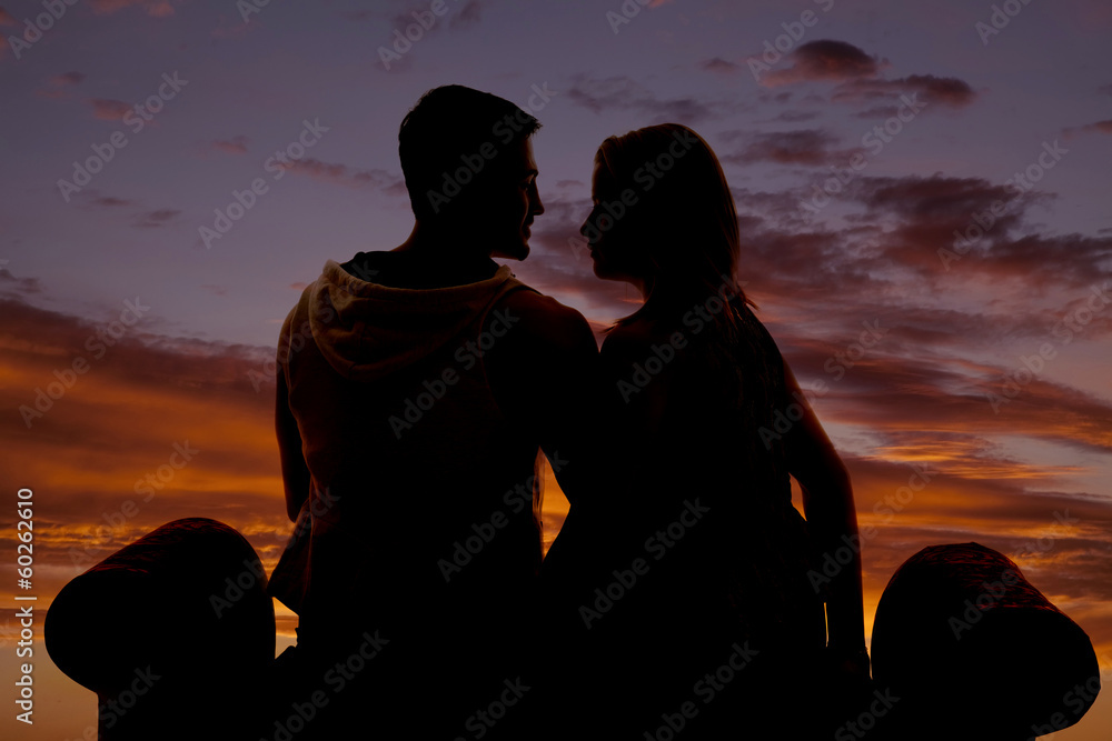 silhouette couple sit on bench facing