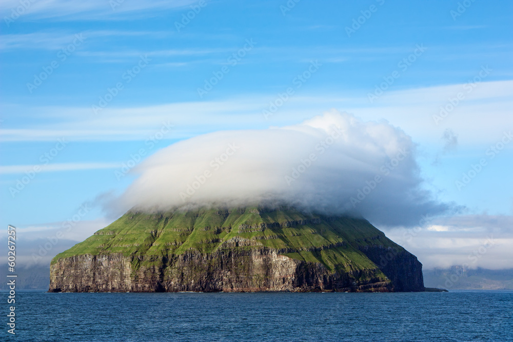 Remote rocky island covered by a curious cloud