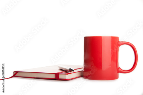 red notebook, pen and cup of tea on white background