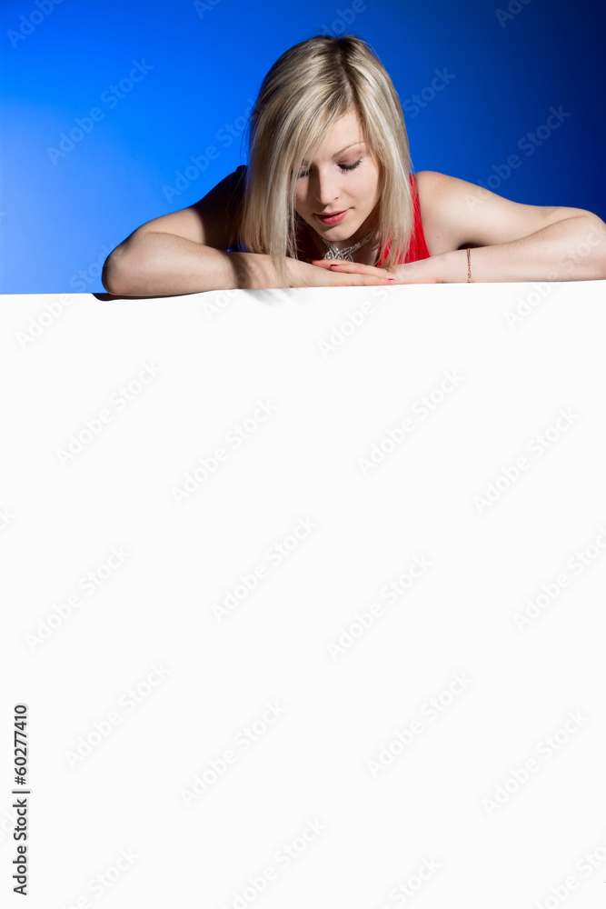 Young girl leans on a big blank white banner and looking down on Young girl leans on a big blank white banner and looking down on