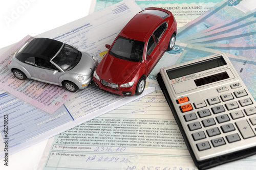 Два автомобиля, калькулятор на фоне полиса, извещения и денег