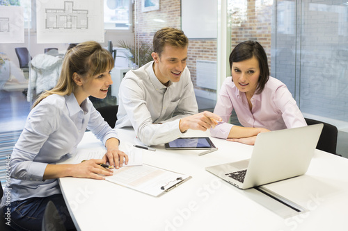 Work team in meeting room working on laptop