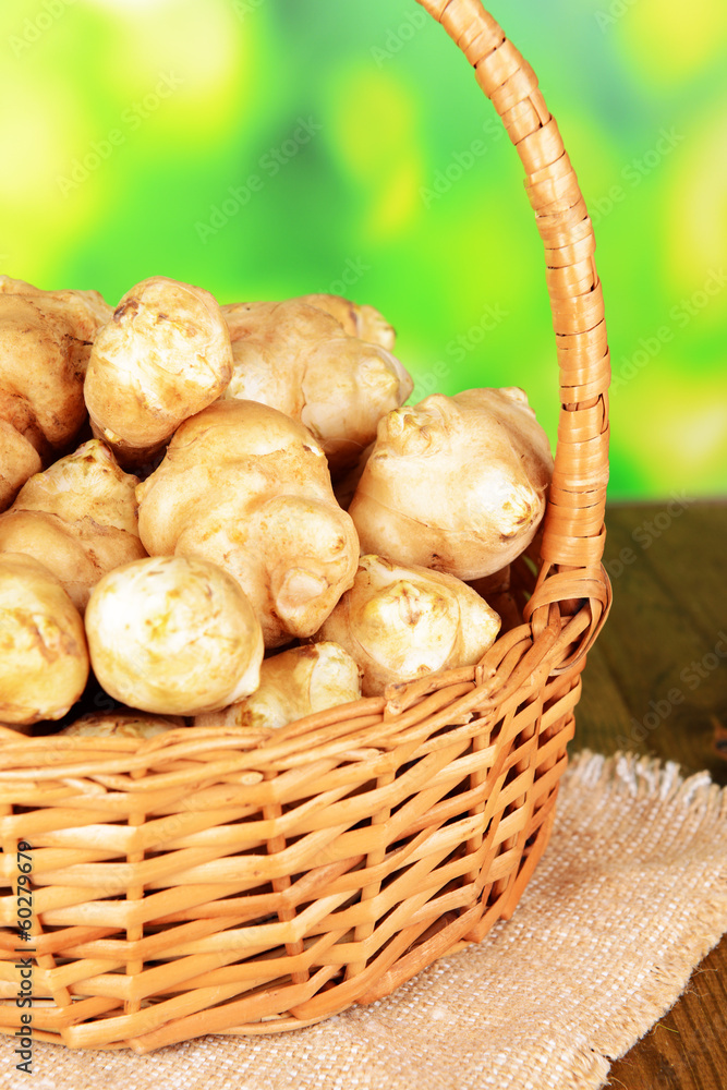 Topinambur roots in wicker basket on table on bright background Topinambur roots in wicker basket on table on bright background