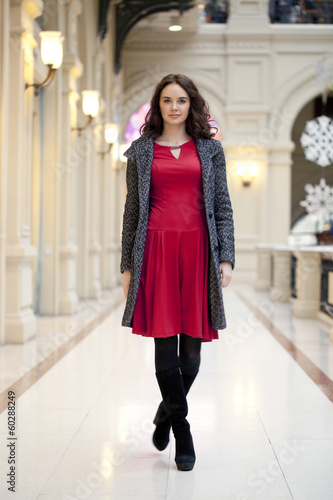 Young beautiful woman in red dress walks in the store