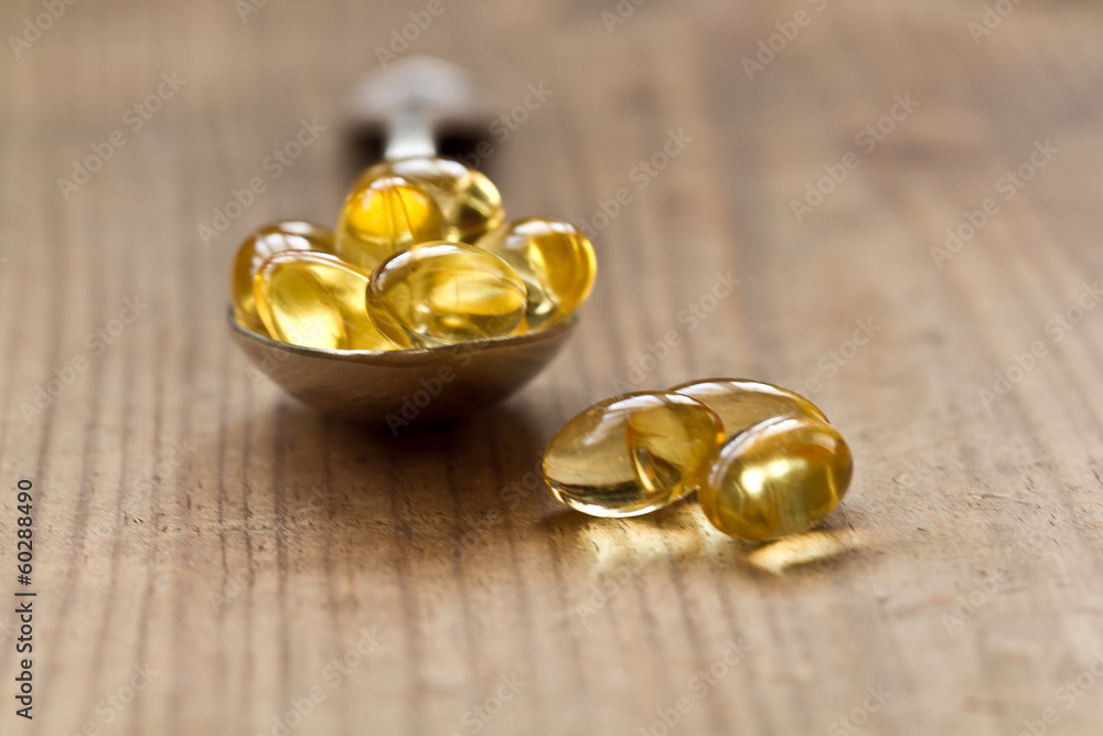 Cod liver oil omega 3 gel capsules isolated on wooden background Cod liver oil omega 3 gel capsules isolated on wooden background