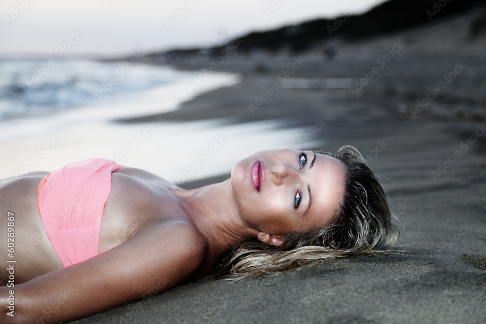 Woman in swimsuit lying on the beach after swimming in the sea.