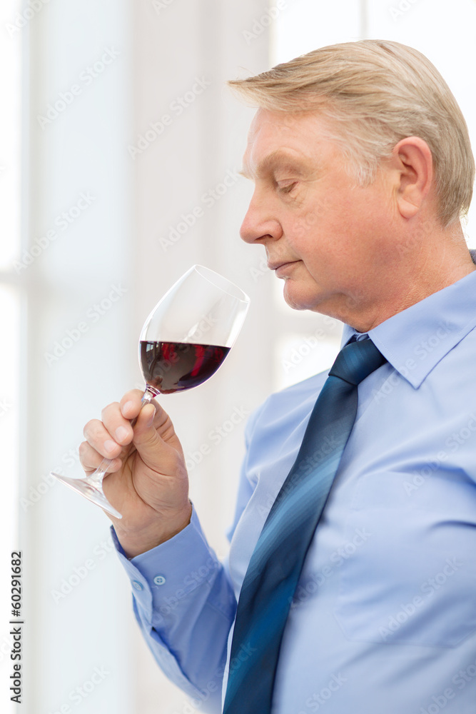 older man smelling red wine older man smelling red wine