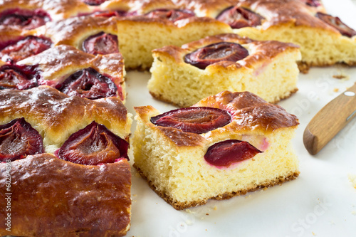 Plum cake and slices of plum cake on a baking paper