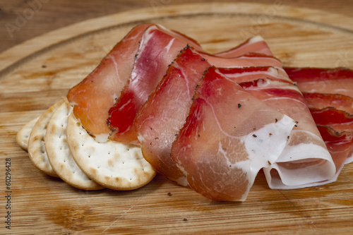 european ham called speck on wooden board with bread slices photo