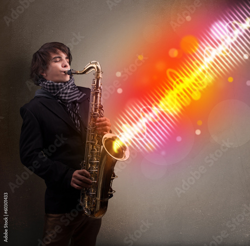 Young man playing on saxophone with colorful sound waves