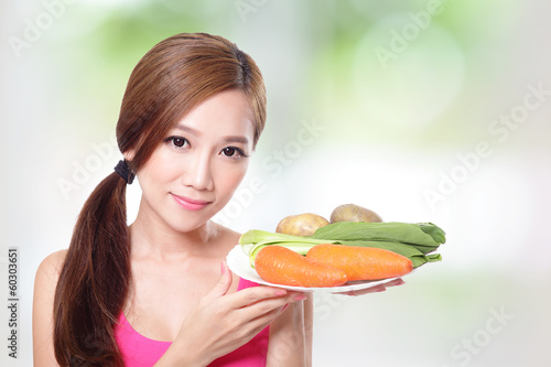 woman holding green vegetables and carrots