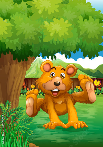 A brown bear playing under the tree at the backyard