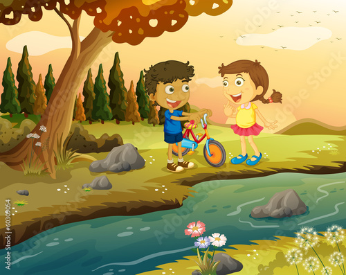 A boy and a girl with a bike standing at the riverbank