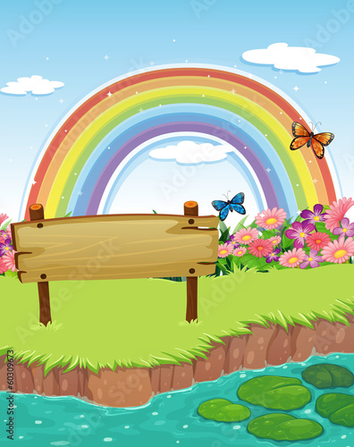 An empty wooden signboard at the riverbank and a rainbow in the