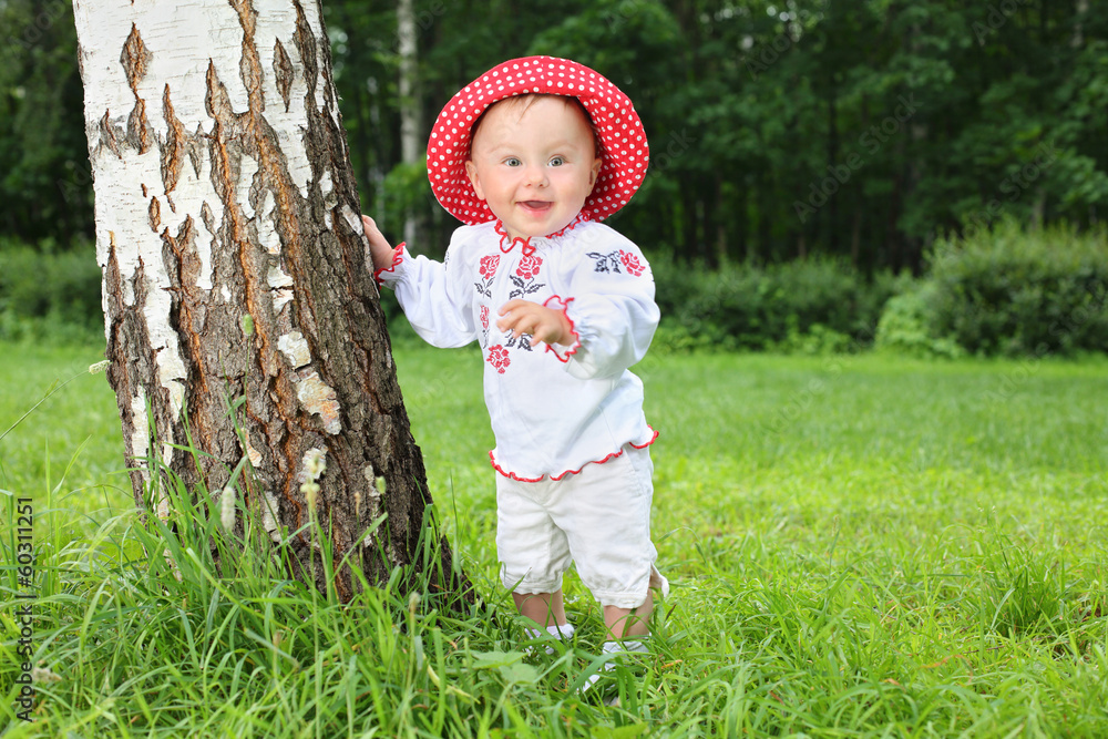 Little girl in folk russian costume near birch tree Little girl in folk russian costume near birch tree