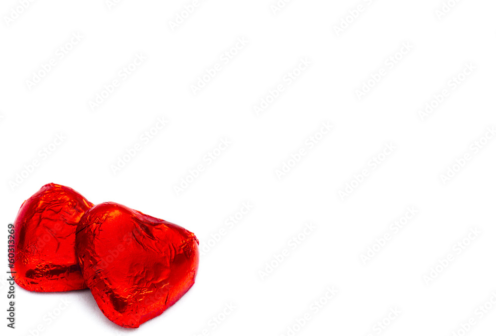 Fototapeta premium Two heart-shaped chocolate pieces on a white background, close-u