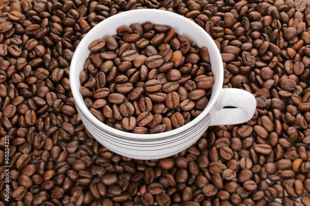 A cup full of coffee beans surrounded by more coffee beans A cup full of coffee beans surrounded by more coffee beans