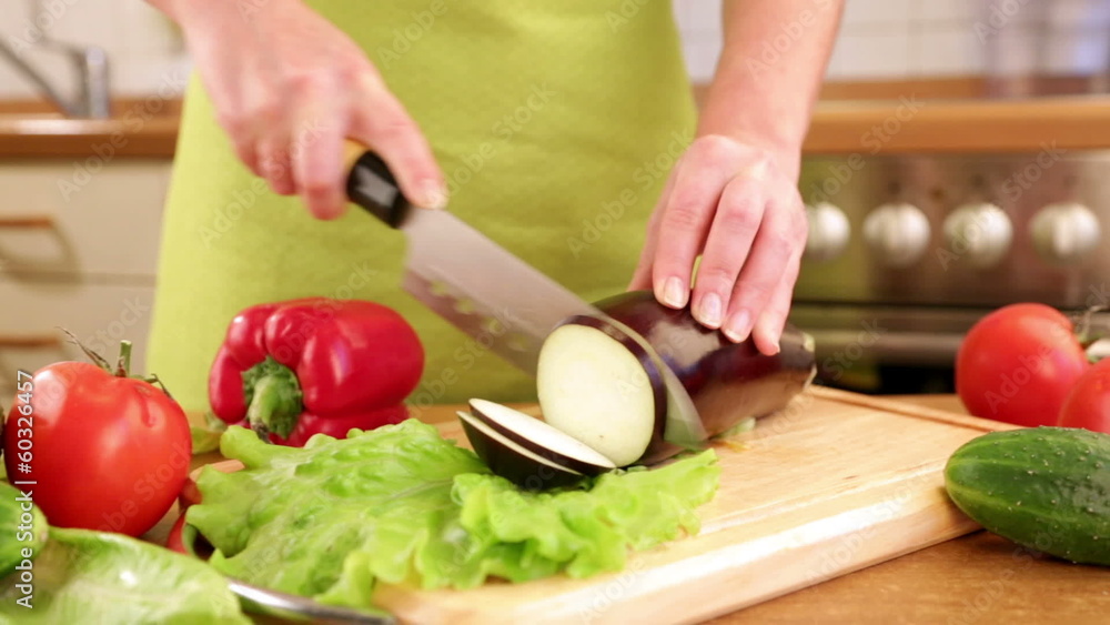 Woman's hands cutting eggplant, behind fresh vegetables. Woman's hands cutting eggplant, behind fresh vegetables.