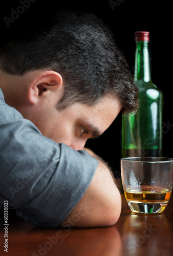 Depressed drunk man staring at a glass of scotch