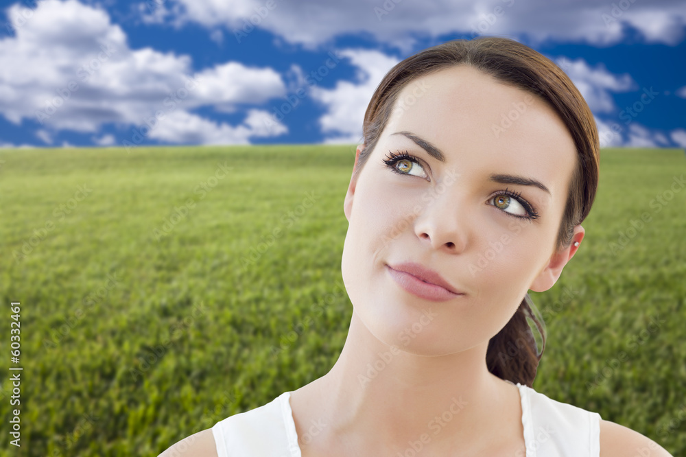 Contemplative Woman in Grass Field Looking Up and Over Contemplative Woman in Grass Field Looking Up and Over