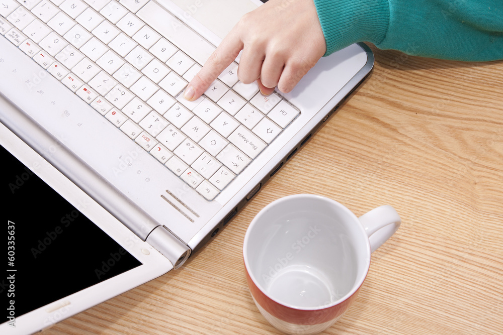 woman with computer in foreground with cup of coffee woman with computer in foreground with cup of coffee