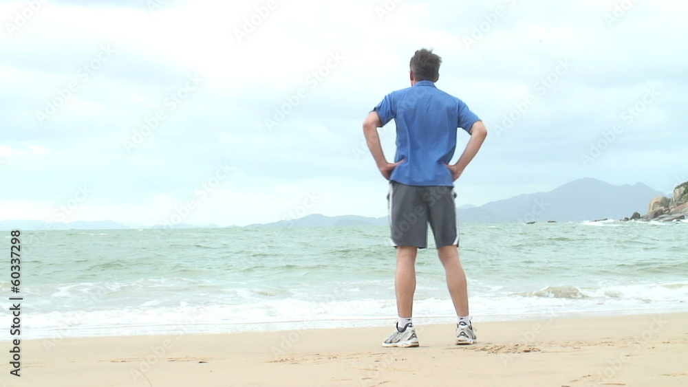 Läufer am Strand macht Aufwärmübungen und läuft los. Läufer am Strand macht Aufwärmübungen und läuft los.