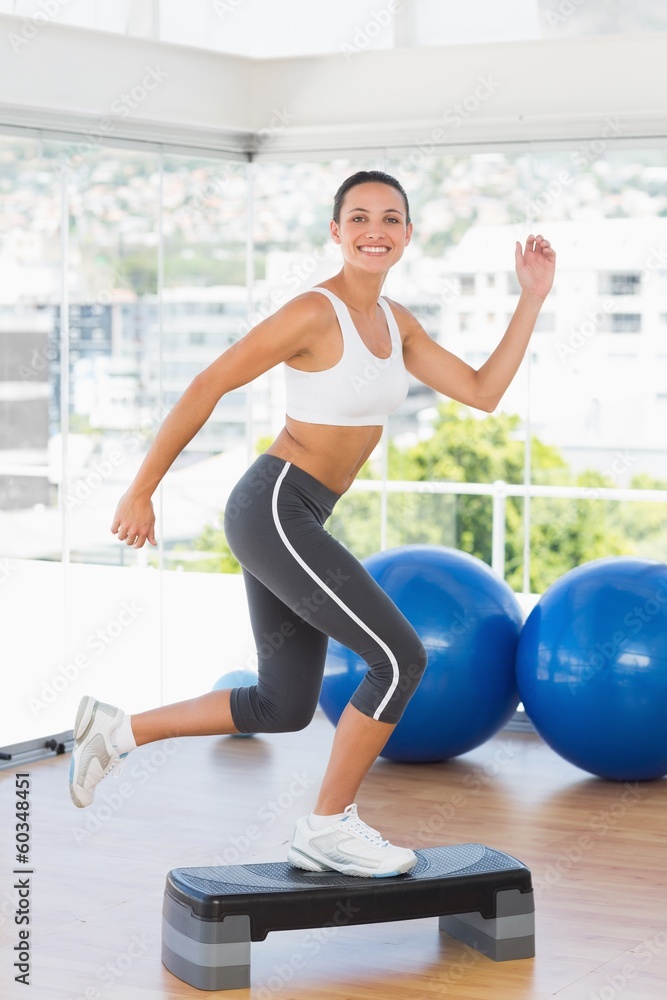 Fototapeta premium Fit young woman performing step aerobics exercise