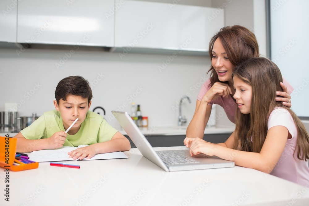 Mother with kids using laptop in kitchen Mother with kids using laptop in kitchen