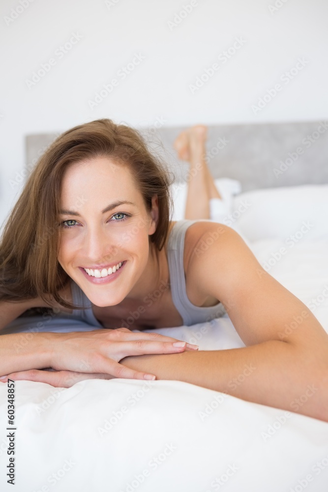 Fototapeta premium Pretty smiling young woman lying in bed