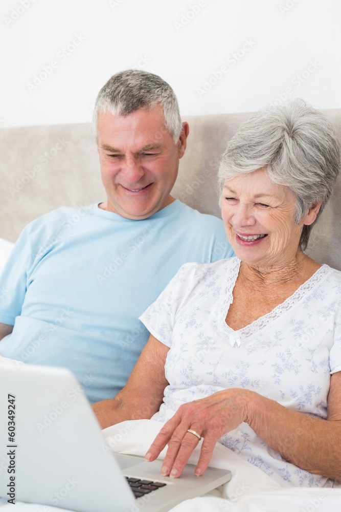 Senior couple using laptop computer in bed Senior couple using laptop computer in bed