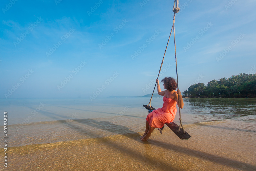 Beautiful girl on a swing at the beach