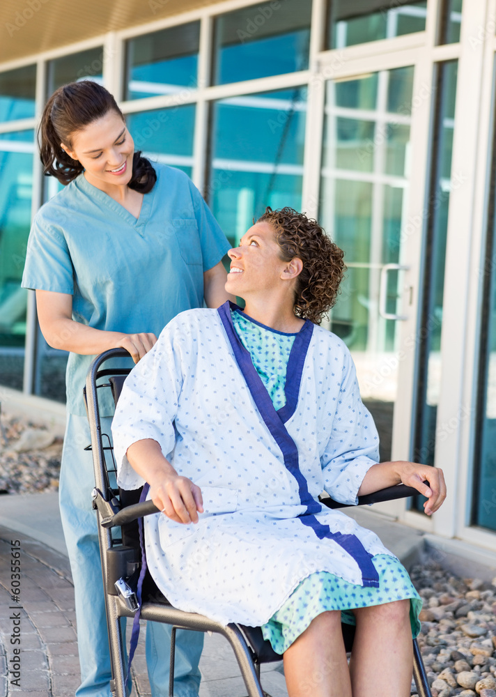 Obraz premium Patient Looking At Friendly Nurse While Sitting On Wheelchair