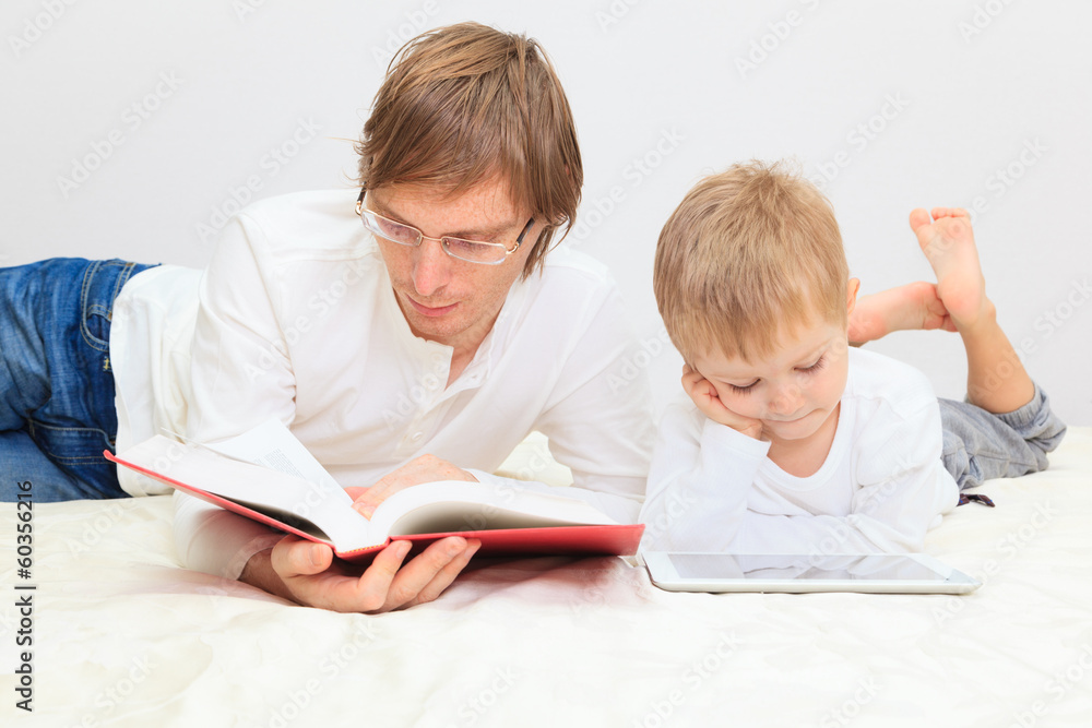 Father reading while son looking at touch pad Father reading while son looking at touch pad