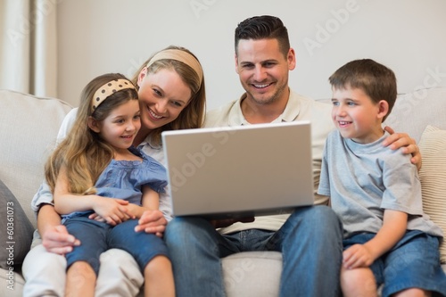 Family using laptop together on sofa