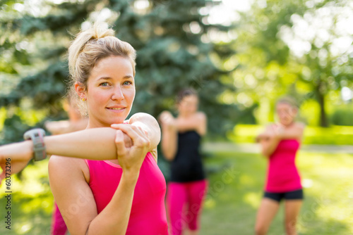 Cheerful young woman streching her arm before jogging