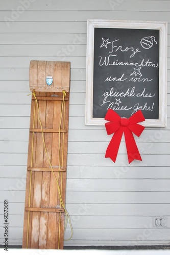 Fototapeta Wooden toboggan propped against exterior grey wall of house
