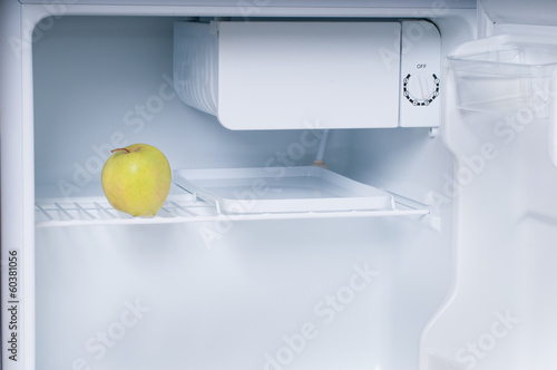 One apple in open empty refrigerator photo