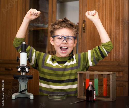 Happy boy with a microscope and colorful flasks. Education.