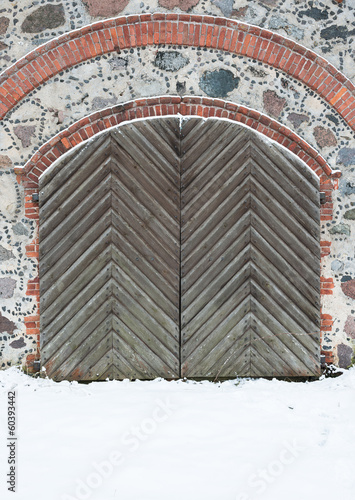 Old wooden gate with pig-iron rivets in a granite wall in the wi