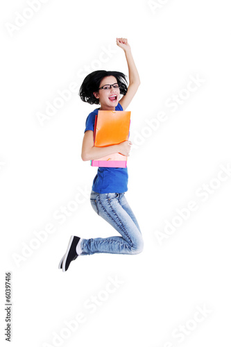 Happy female student jumping with a notebook