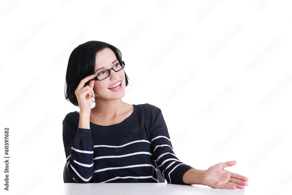 Woman sitting at the desk and showing something Woman sitting at the desk and showing something