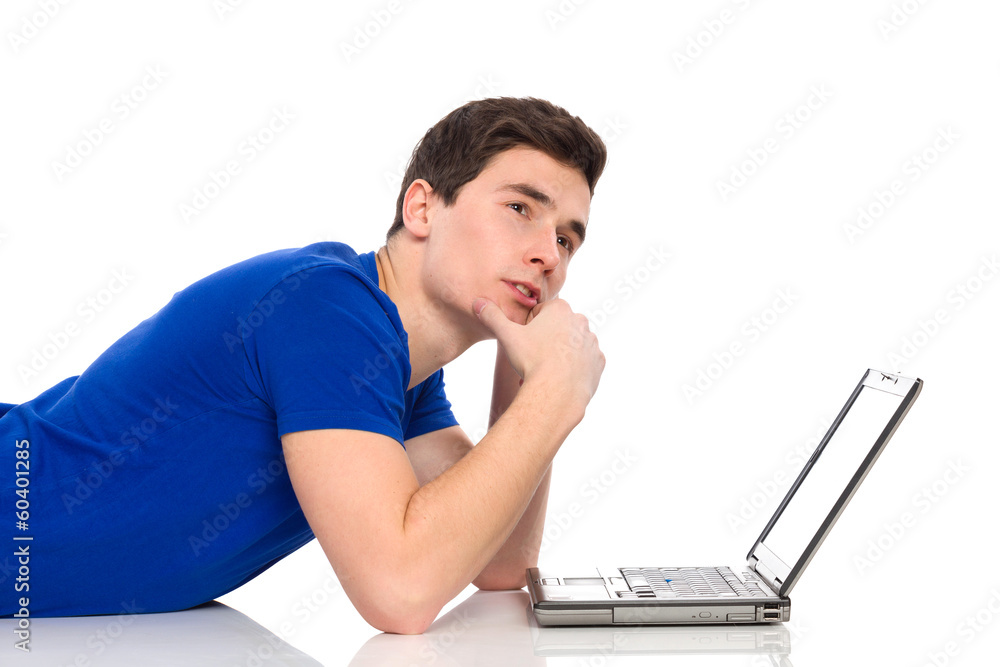 Thinking male student with laptop lying on the floor. Thinking male student with laptop lying on the floor.