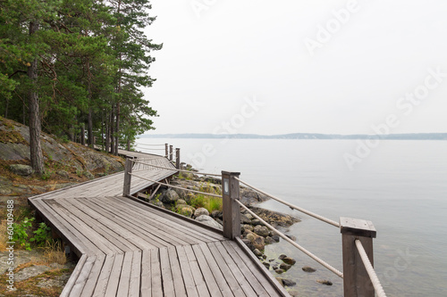Fototapeta Rocky lakeshore with wooden pathway