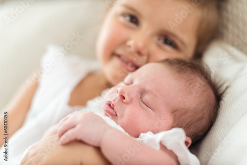 Newborn in a christening dress in her sister