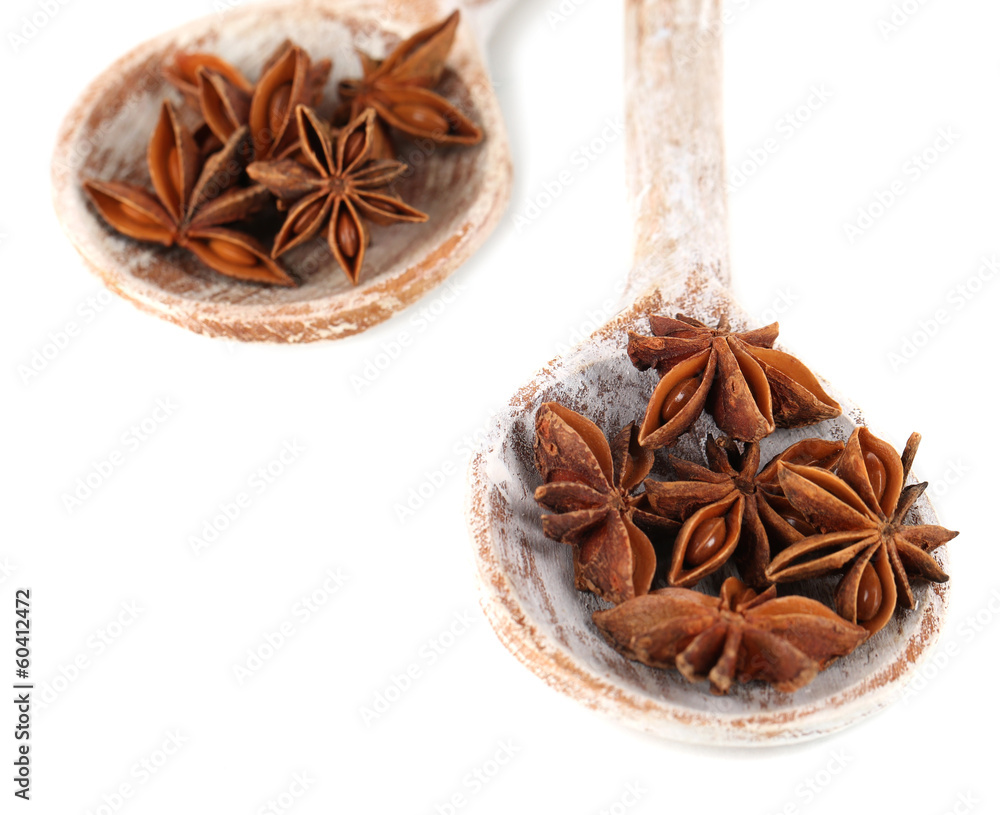 Star anise in wooden spoons, isolated on white