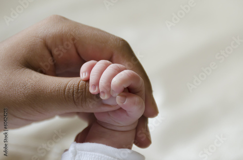 Baby hand holding an adult's finger