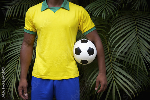 Brazilian Football Player Holding Soccer Ball in Jungle photo