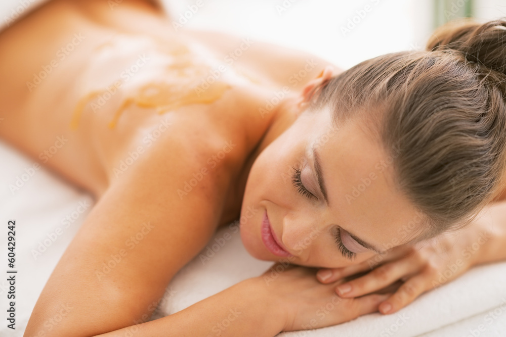Young woman with honey on back laying on massage table Young woman with honey on back laying on massage table